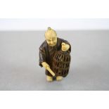 A vintage signed carved chinese netsuke of an oriental man with bird cage.