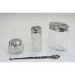 A collection of hallmarked silver items to include three silver topped vanity jars and a button hook