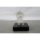 A vintage frosted glass car hood ornament / mascot of a bird mounted on a black glass base.
