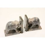 A pair of carved stone bookends in the form of elephants pushing books