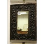 An antique oak mirror with carved stylized dragon and dolphin figures four leaf clovers and fleur de
