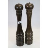 A pair of oversized wooden pepper grinders