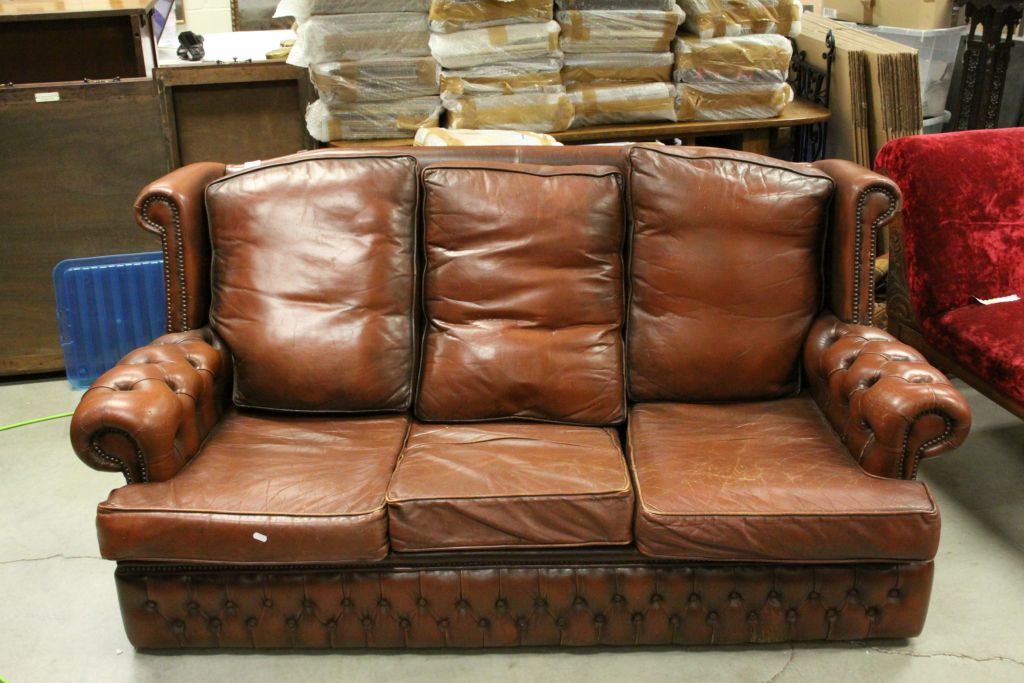 A brown leather three seater chesterfield style sofa.
