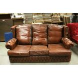 A brown leather three seater chesterfield style sofa.
