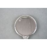 A hallmarked silver dressing table mirror with green man and bird decoration.
