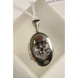 Silver locket with embossed image of a dog with ruby eyes