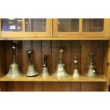 Five vintage Hand Bells of varying sizes all with Wooden handles plus an Asian example with Cow