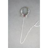 A silver Magnifying glass in the form of a bow with ruby cabochon