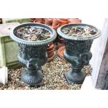 Pair of cast iron garden urns of classical form together with a pair of composite stone plinth bases