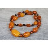 Butterscotch amber bead necklace, seventeen oval amber beads with faceted plastic bead spacers,