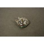 A silver dog brooch on emerald platform