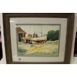 Signed watercolour of boats in a yard by a boathouse