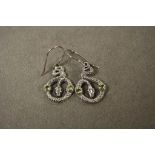 A pair of silver and snake shaped earrings with peridot cabochons