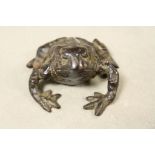 A bronzed metal figure of a frog.