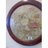 Pair of circular well worked embroidered silk pictures depicting a cluster of flowers, circular
