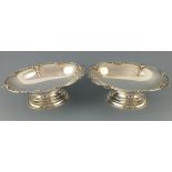 A pair of silver dishes, Birmingham 1928, Walker & Hall, the shaped oval bowls raised on a foot