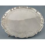 A circular silver salver, Chester 1907, Barker Bros., with an ogee edge and engraved with foliage,