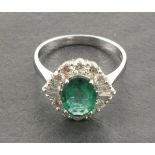 An 18ct white gold emerald and diamond ring, the central oval shaped emerald has a carat weight of
