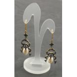 A pair of ornate drop earrings set with diamonds and suspended pearl