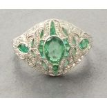 Platinum emerald and diamond ring, set with an oval emerald, interpierced ornate diamond and emerald
