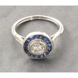 A platinum sapphire and diamond target style ring, set with an old cut diamond surrounded by calibre