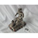 CONTINENTAL CAST FIGURE OF A SEATED TRADESMAN, decorated with coloured glass, 3.75” long 205g.