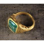 A French Mediaeval Gold Ring set with an emerald (A/F) and decorated with scrolling stems of ball