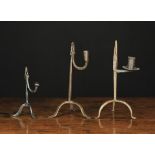 Three Wrought Iron Rushnips on tripod bases; Two early 19th century with candle sockets, 10 ins (25.