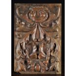 A Fine 16th Century Oak Panel carved in relief with a face mask of a Green Man flanked by upswept