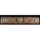 A 17th Century Carved Oak Drawer Front with a protuberant cherub's head festooned in beads to the