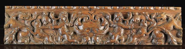 A 17th Century Flemish Carved oak Drawer Front decorated with winged cherubs blowing hunting horns,