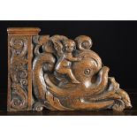 A 17th Century Flemish carved Oak Flanking Panel depicting a winged cherub riding on the back of a