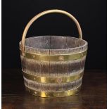 A 19th Century Coopered Oak Pail bound in brass straps and fitted with a brass swing handle,