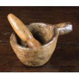 A Small 18th Century Dug-out Treen Mortar with protuberant side handle and accompanying pestle.