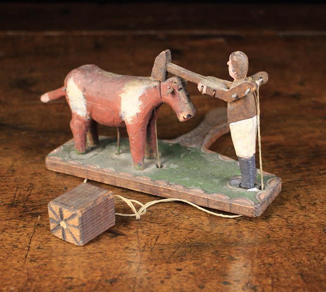 A Delightful Antique Carved Wooden Folk Art Toy with a hand-held paddle surmounted by an