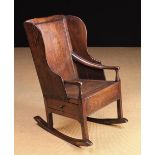 A 19th Century Oak Panel Back Rocking Chair with winged sides and a box form seat enclosing