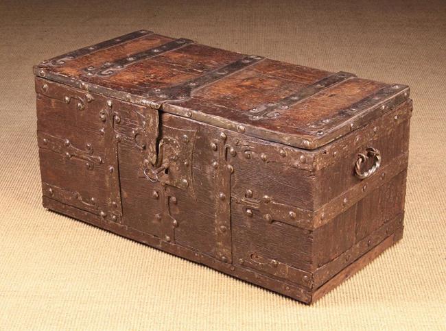 A 16th Century Boarded Oak Chest of rectangular form bound in studded iron straps with fleur-de-lis