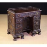 A Small Antique Kneehole Desk carved in the Chinese Chippendale Style with blind-fretted