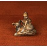 A Small Japanese Carved Hardwood Netsuke in the form of a child sat upon the back of a reclining