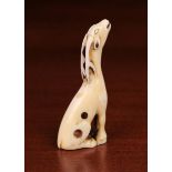 An 18th Century Kyoto School Ivory Netsuke carved in the form of a slender seated deer giving voice