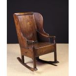 A 19th Century Joined Oak Rocking Lambing Chair having a panel back, winged sides,