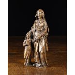 A 16th/17th Century Walnut Carving of St Anne holding the hand of the diminutive figure of Mary,