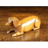 A 20th Century Carved Mahogany Dog depicted lying down with inset nail head eyes,