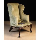 An Early 18th Century Winged Armchair in need of re-upholstery, having a tall back,