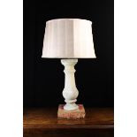 A Stone Baluster mounted as a side lamp with shade;