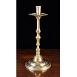 A Tall 17th Century Brass Candlestick with cylindrical socket above a flared drip pan and knopped