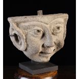 An Antique Stone Relief Carved Face Mask of an Imp with pointed ears and mischievous though benign