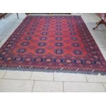 A large hand knotted woollen rug with a red field in good condition, minimal wear - 410cm x 306cm