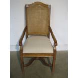 A modern armchair with caned back and upholstered seat in clean condition