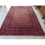 A hand knotted woollen rug with a marroon field, some small wear mainly to edges, and some